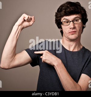 a weak feeble geek nerd young man with thin arms wearing glasses flexing his muscles Stock Photo