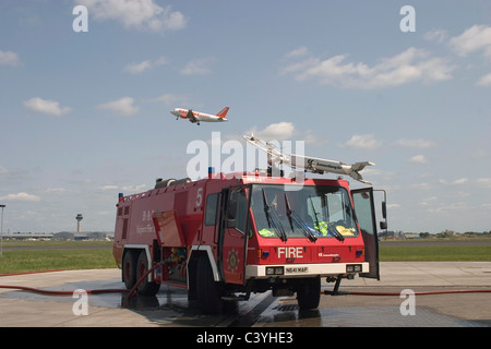 Airport fire engine with plane flying overhead Stock Photo