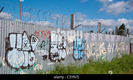 Graffiti on metal fence with barbed wire Stock Photo