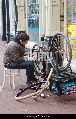 man sitting repairing bicycle on street Stock Photo