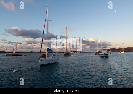Sailboats moored in early morning light with pink clouds and moon setting at Marina Cay on Tortola in British Virgin Islands Stock Photo