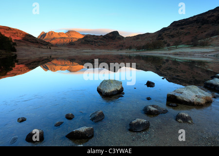 Late autumn light on the icy edges of a calm Blea Tarn in the Lake District of England Stock Photo