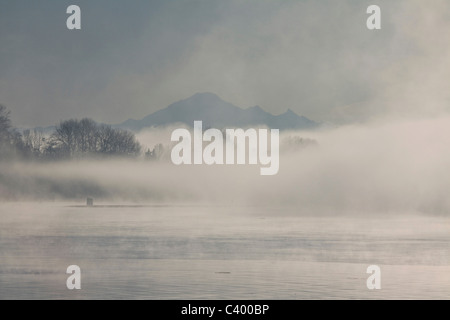 Mount Baker rises through fog on the Fraser River. Port Coquitlam, BC, Canada. Stock Photo
