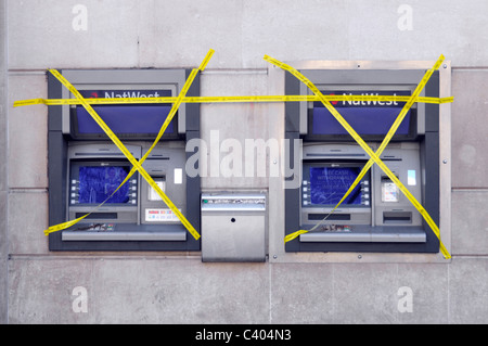 NatWest bank branch premises external outdoor atm cash machines two out of order hole in wall covered in yellow tape Charing Cross London England UK Stock Photo