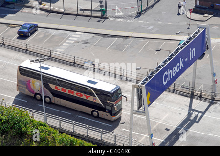Aerial birds eye view looking down on top of double decker coach bus passing below check in gantry sign leaving Dover ferry Port Kent England UK Stock Photo