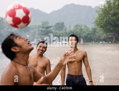 Guys playing football on beach Stock Photo