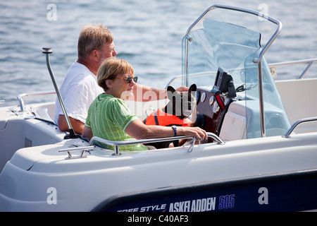 Couple in motor boat slowly cruising in the harbor. Stock Photo