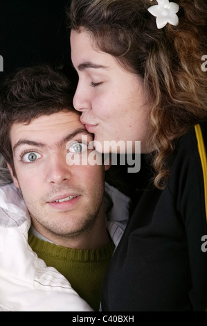 Portrait of young woman kissing surprised man Stock Photo