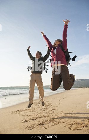 Young backpackers jumping on beach Stock Photo