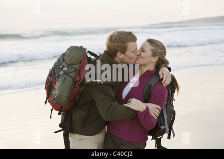 Backpacking couple kissing at beach Stock Photo
