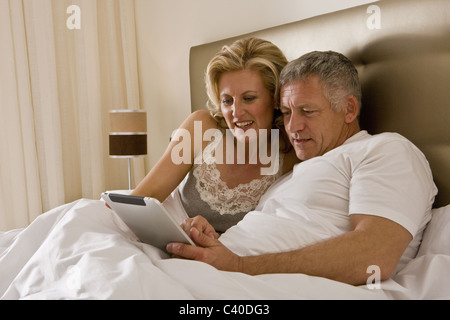 Couple in bed using tablet computer Stock Photo