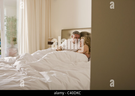 Mature couple embracing tenderly in bed Stock Photo