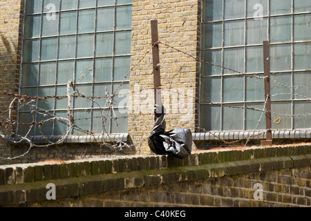 London , Kings Cross , derelict factory unit protected by barbed wire or razor wire security brick wall Stock Photo