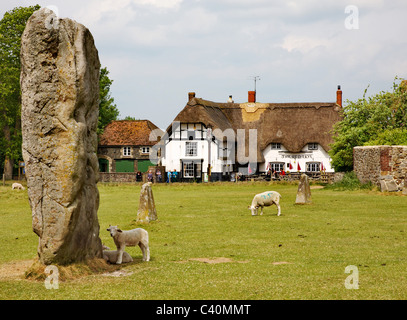 Massive sarsen monolith in one of the  inner stone circles of Avebury in Wiltshire with the Red Lion village pub Stock Photo