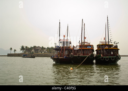 Horizontal view of traditonal wooden junks used for guided tours moored in Halong Bay. Stock Photo