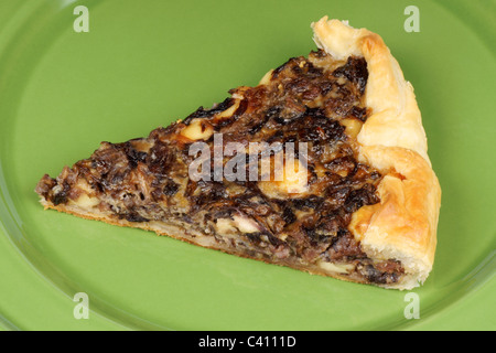 Slice of rustic french quiche with red chicory, bacon and cheese over a green ceramic dish Stock Photo