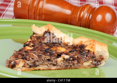 Slice of rustic french quiche with chicory, bacon and cheese over a green ceramic dish Stock Photo