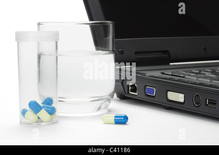 Pills and glass of water next to laptop - conceptual image of IT work related stress Stock Photo