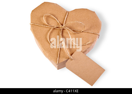 Photo of a heart gift box wrapped in brown paper with label, isolated on a white background. Stock Photo