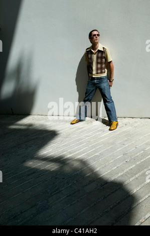 Full length portrait of Paulo Furtado, aka Legendary Tigerman, with sunglasses standing in the sun against a grey wall Stock Photo