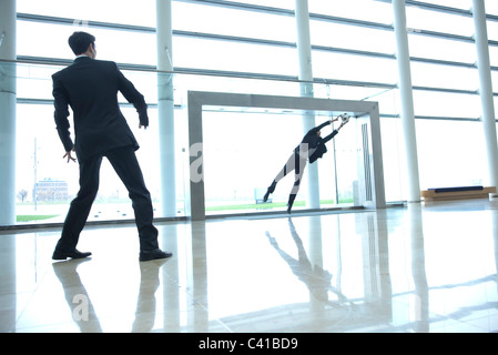 Businessmen playing soccer in lobby Stock Photo