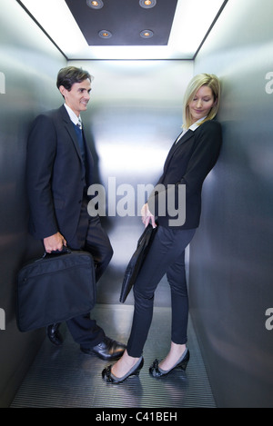 Colleagues playing footsies in elevator Stock Photo