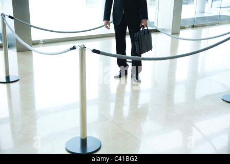 Businessman standing inside roped off area in lobby Stock Photo