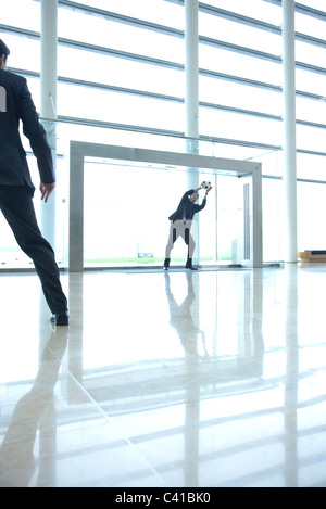 Businessmen playing soccer in lobby Stock Photo