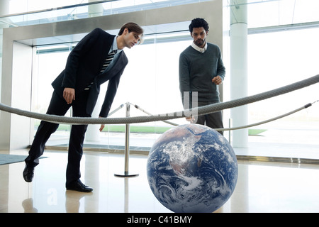 Businessmen looking at ball in lobby Stock Photo