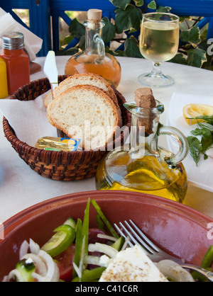 SELECTIVE FOCUS IMAGE OF OLIVE OIL AND BREAD IN A GREEK TAVERNA WITH SALAD IN THE FOREGROUND Stock Photo