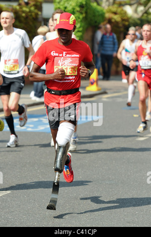 a Disabled Runner with a artificial leg takes part in the Virgin 2011 London Marathon seen here at 14 Miles Stock Photo