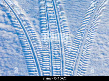 Car tyre tracks going different directions on snow , Finland Stock Photo