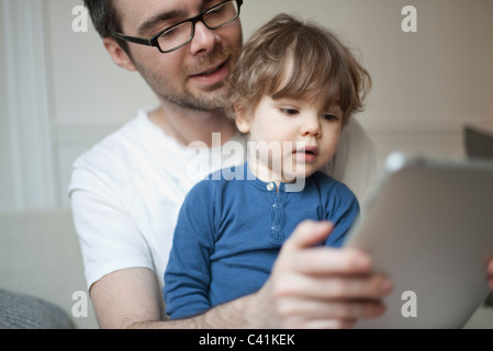 Toddler boy watching father using digital tablet Stock Photo