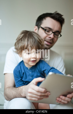Father and young son looking at digital tablet together Stock Photo