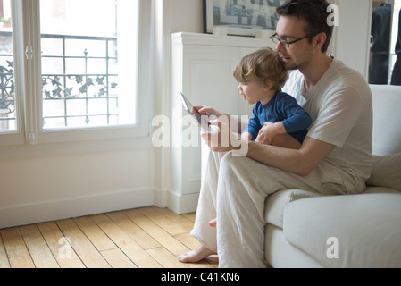 Toddler boy watching father using digital tablet Stock Photo