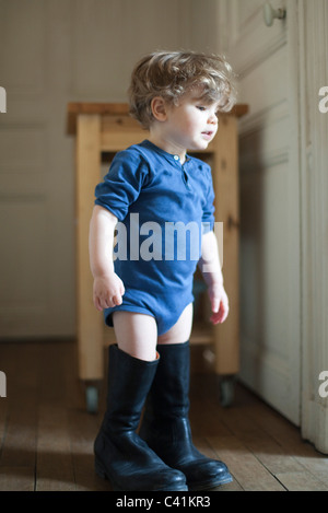 Toddler boy wearing father's boots Stock Photo