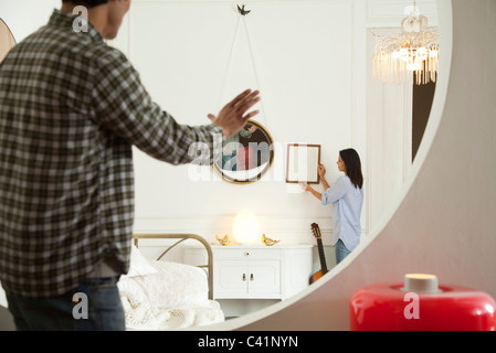 Couple hanging framed art in home Stock Photo