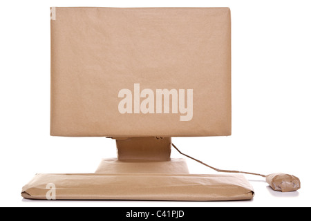 Photo of a computer wrapped in recycled brown paper, isolated on a white background. Stock Photo