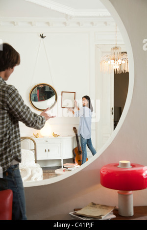 Couple hanging framed art in home Stock Photo