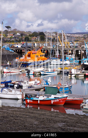 Newlyn harbour at low tide with the RNLI Penlee lifeboat and other fishing boats and trawlers, with a sunny and cloudy sky above Stock Photo