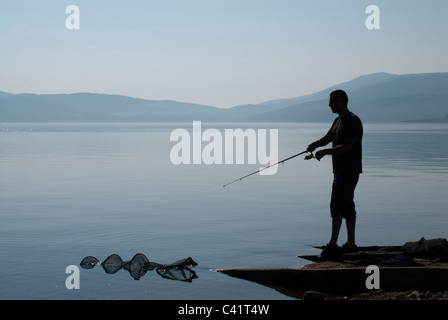 fisherman,silhouette,on,a,beach,with,fishing,rod Stock Photo