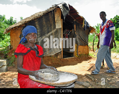 A liberian family by their home. Woman making bread from cassava (manioc) Stock Photo