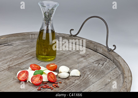 halved tomatoes with slices of mozzarella and flavored olive oil, garlic and peppers Stock Photo