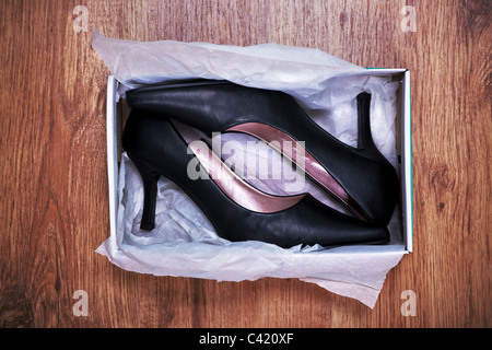 Photo of a pair of new womens court shoes in a shoe box on rustic wooden floor. Stock Photo