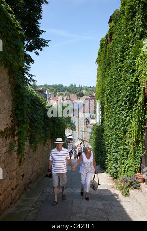 Two people holding hands walking up old street in Sarlat-la-Caneda Dordogne France Stock Photo