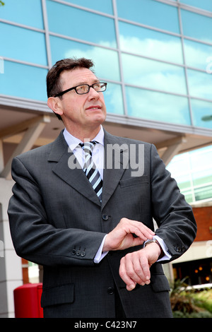 Businessman with glasses checking his watch Stock Photo