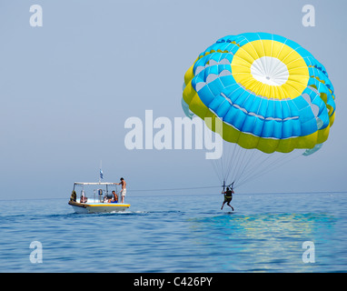Paraglider airborne being towed by a boat at sea Stock Photo