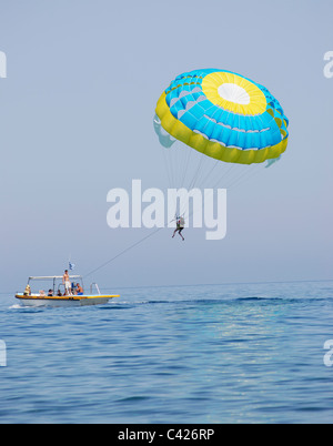 Paraglider airborne being towed by a boat at sea Stock Photo