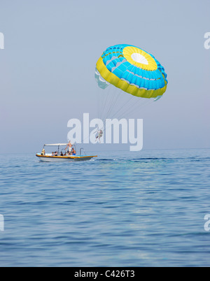 Paraglider airborne being towed by a boat at sea Stock Photo