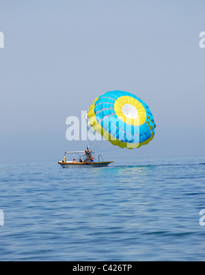 Paraglider airborne being towed by a boat at sea Stock Photo